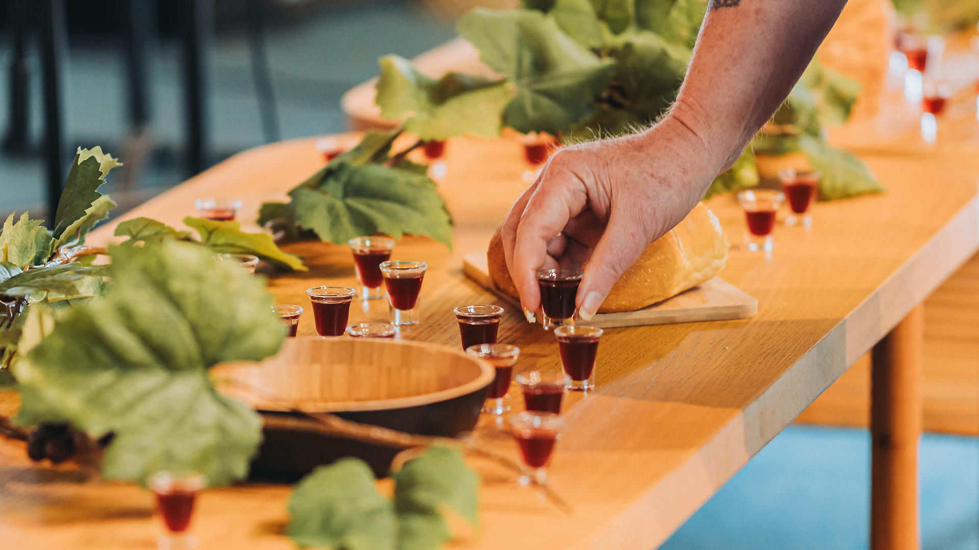 A person grabbing a communion cup from a table